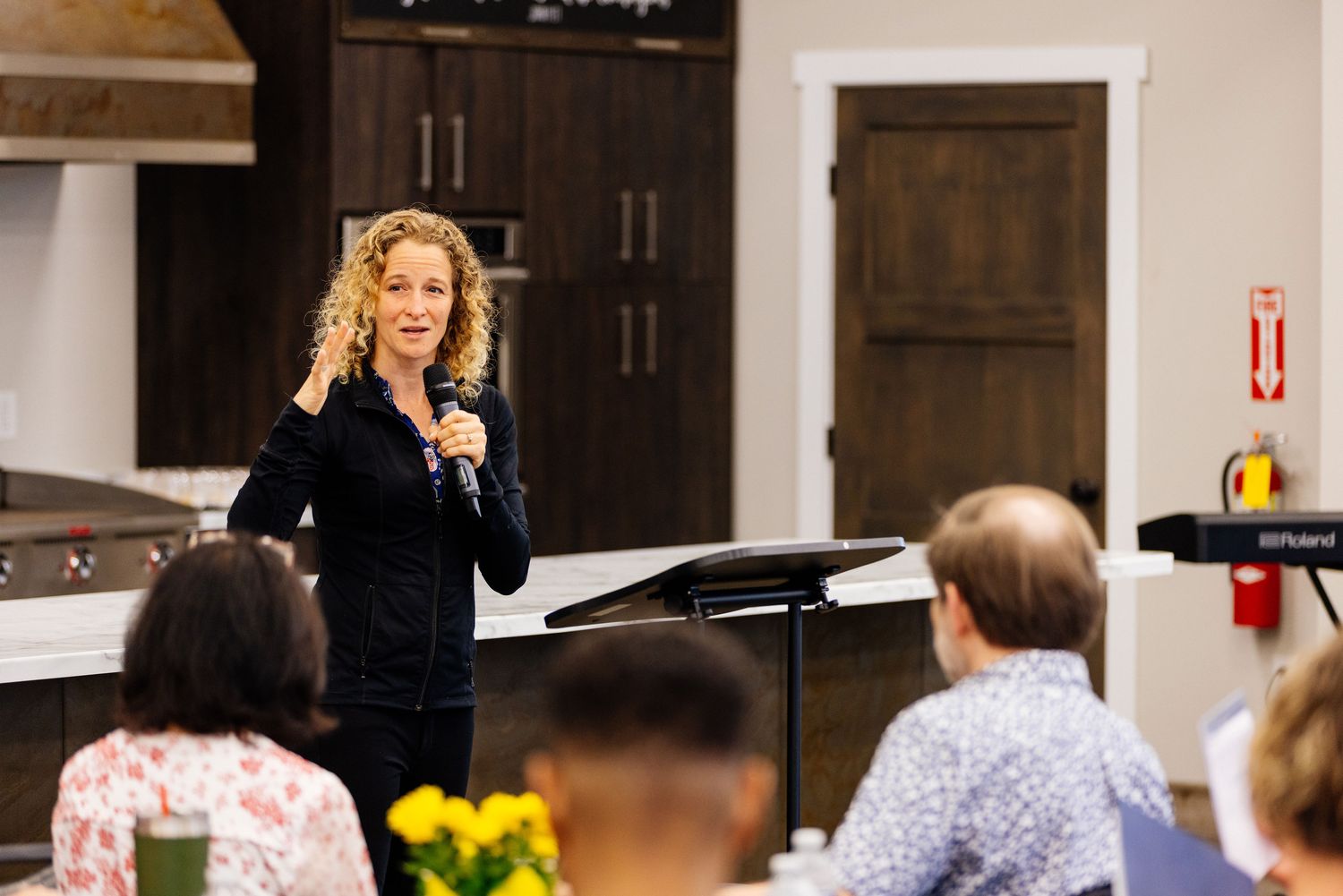 Amy speaking with a microphone at a gathering